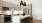 Apartments for Rent Near Oak Cliff, TX - Oakhouse - Modern Kitchen with Stainless Steel Appliances, Elegant Quartz Countertops, Large Cooking Island with Chic Black Hanging Lights, White Tile Backsplash, Off-White Cabinetry, and Underglow Lighting