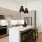Apartments for Rent Near Oak Cliff, TX - Oakhouse - Modern Kitchen with Stainless Steel Appliances, Elegant Quartz Countertops, Large Cooking Island with Chic Black Hanging Lights, White Tile Backsplash, Off-White Cabinetry, and Underglow Lighting
